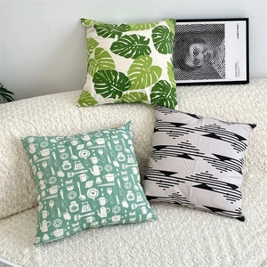 Three cotton linen pillow covers with green leaf and geometric patterns on a white sofa