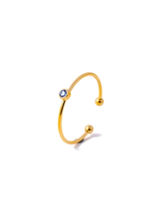 Macro detail of gold-plated C-shaped ring featuring a bezel-set blue zircon stone
