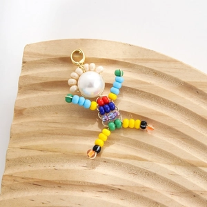 Handmade beaded doll pendant with white pearl head and colorful beads on wood