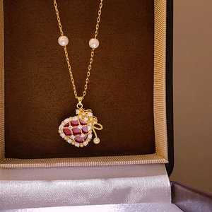 Macro detail of gold plated necklace with red stone lucky bag pendant and white pearls