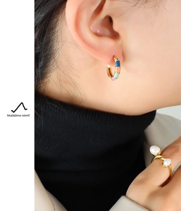 Gros plan détaillé de boucles d'oreilles émaillées colorées et bague double perle en acier