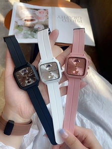 Close-up of three stylish square dial watches in black, white and pink with silicone straps