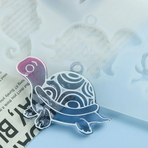 Gros plan d'un pendentif tortue en résine avec moule en silicone sur fond bleu clair