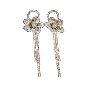 Boucles d'oreilles fleurs avec perles blanches et franges de strass sur fond blanc épuré