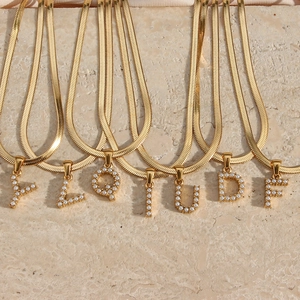 18K gold plated snake chain necklace with pearl initial pendants on marble stone