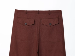 Detailed back view of dark brown trousers with buttoned flap pockets and textured fabric