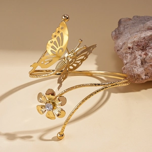 Detail of golden butterfly arm cuff featuring hollow wings and a sparkling rhinestone
