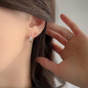 Close-up of S925 silver flower hoop earrings and trendy chain ring on a female model