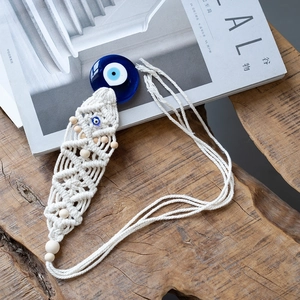 Detail of handmade woven macrame wall hanging with blue glass evil eye glass and wooden beads