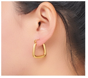Close-up of a model wearing a minimalist golden U-shaped geometric earring with high polish