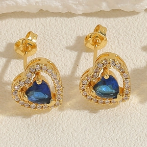 Macro shot of 14K gold plated heart stud earrings featuring a central blue zircon gemstone