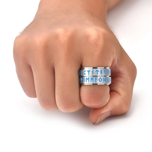 Close-up of rotating Viking rune ring with blue engraved letters on brushed steel surface