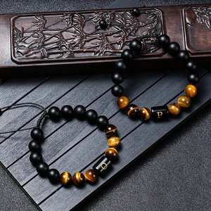 Detail of beaded bracelets with tiger eye stones and custom engraved P and O letter beads