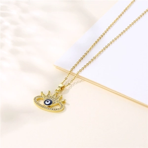 Gold evil eye necklace with blue zircon pendant and fine link chain on beige background