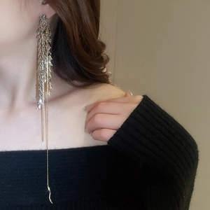 Gros plan de boucles d'oreilles à pompons longs en métal bicolore sur un mannequin