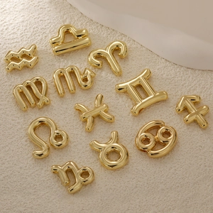 Set of 12 gold plated bubble 12 zodiac sign pendants on beige textured background