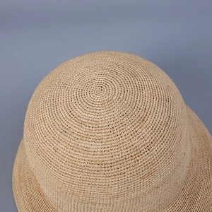 Detailed top view of the fine spiral weave pattern on a natural raffia straw hat