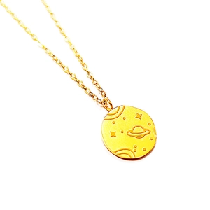 Macro detail of 18K gold plated celestial pendant featuring embossed planet and stars