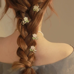 Elegant gold flower hair clips with pink and white enamel petals worn on a braided hair