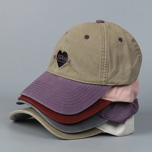 Close-up of stacked washed cotton baseball caps featuring embroidered heart-shaped logo