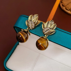 Gros plan de boucles d'oreilles vintage en bronze avec pierre oeil de tigre et boîte