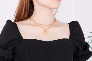 Close-up of a double-layered gold butterfly pendant necklace worn by a fashion model