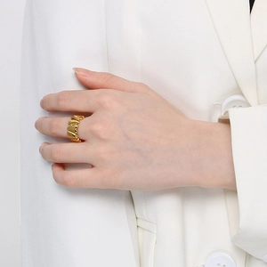 Detail of 18K gold stainless steel ring with textured wavy design on model's hand