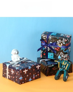 Close-up of gaming and space themed gift wrapping paper with decorative ribbons