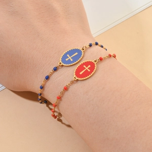 Detail of gold chain bracelets with blue and red enamel beads and cross charms on a wrist