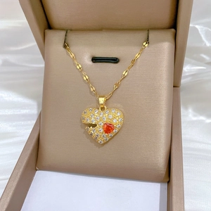 Macro detail of gold heart necklace with pave white zircon and a red gemstone accent