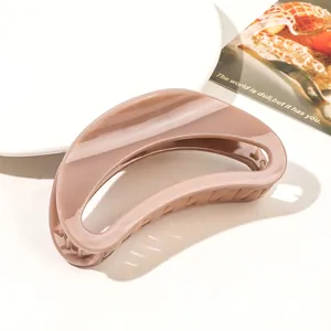Detail of a large glossy nude brown hair claw clip with a hollow crescent design