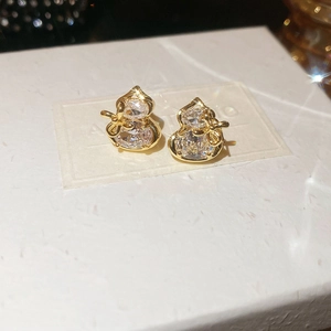 Macro shot of gold plated gourd earrings with zircon stones and a bow detail