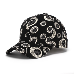 Detailed view of black baseball cap featuring white floral clover prints and curved brim