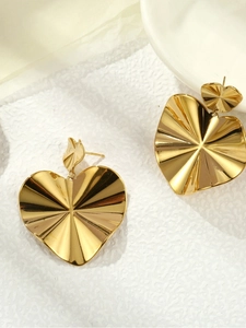 Detail of golden double heart stud earrings with textured radiating finish on white paper