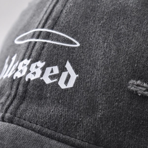 Macro detail of gothic 'Blessed' print on vintage washed grey cotton baseball cap