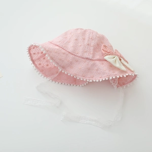 Detailed view of pink baby sun hat with lace fabric, pom poms and a polka dot bow