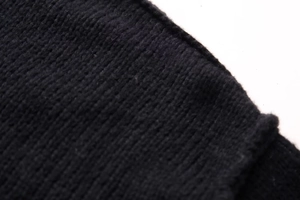 Close-up detail of soft black knitted fabric with a fine vertical ribbed texture