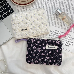 Floral quilted cotton pouches in white and black with woven labels and zipper closures