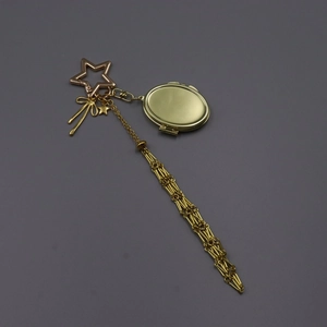 Gold metal keychain with star clasp, bow charm, locket and long mesh tassel detail