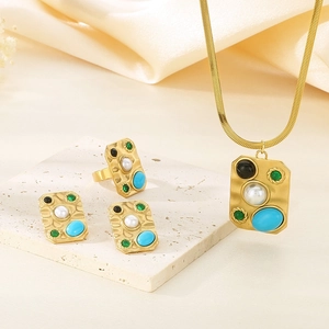Close-up of vintage gold jewelry set with turquoise and pearls on silk backdrop