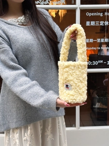 Cream yellow plush tote bag with cartoon patch embroidery held by a model outdoors
