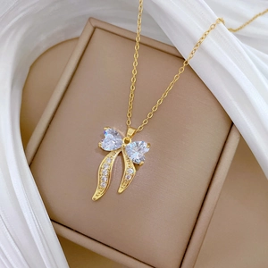 Luxurious gold bow pendant necklace with sparkling crystals on silk background