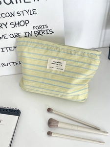 Detailed macro view of yellow striped canvas makeup bag with soft fabric texture