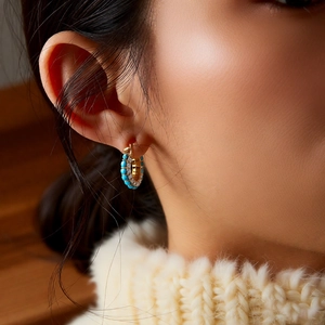 Close-up of gold-plated resin earrings with turquoise beads and zircon on model