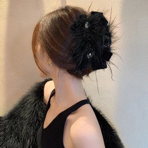 Vue détaillée de la pince à cheveux en plumes noires avec nœud en velours et perles