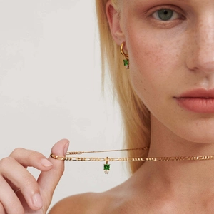 Dettaglio di modella con set di gioielli d'oro e ciondoli in zircone verde quadro