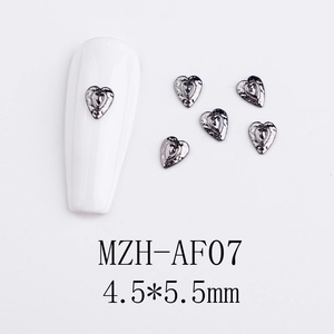 Macro detail of gothic black heart alloy nail charms with textured hammered finish