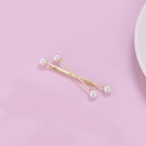 Detail of two gold hairpins with white pearls on a pink background for women's styling
