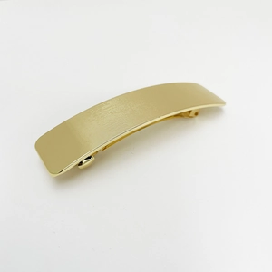 Detailed close-up of golden alloy spring hair clip with horizontal stripe texture