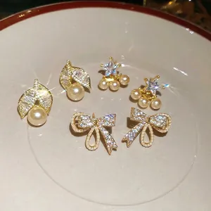 Elegant gold-plated pearl earring set with stars and butterfly motifs on a cream plate